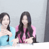 two girls are sitting at a table one wearing a pink shirt that says ' as i love you '