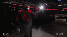 a man in a black and red jacket is standing on a stage in front of a crowd and the words usa live on the bottom