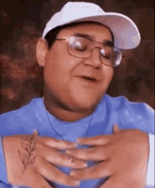 a man wearing glasses and a white hat has a tattoo on his arm