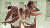 a group of women in white lingerie are dancing in a room