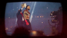 a group of men are standing on a stage holding a wrestling championship .