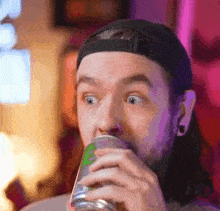 a man in a baseball cap is drinking from a can