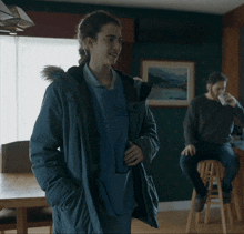 a woman in a parka with a fur hood talks to another woman