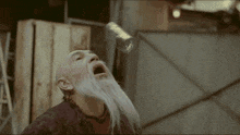 a bald man with a beard is drinking water from a can .