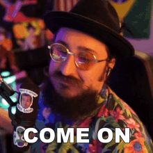 a man wearing glasses and a hat says come on in front of a microphone