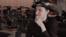 a man wearing a hat with feathers on it looks to the side