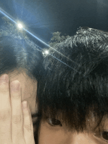 a person covering their face with their hand with a light shining on their head