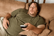 a man is laying on a couch holding a remote