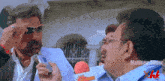 a man wearing sunglasses talks into a microphone with matinee studios written on the bottom right