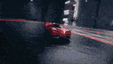 a red sports car is driving down a track in a dark room
