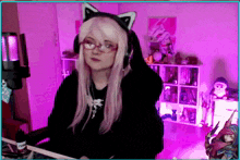 a girl wearing headphones and a cat ear headband is sitting in front of a computer .