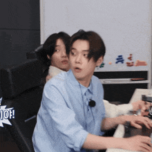 a man in a blue shirt is sitting at a desk with a sticker that says i love you on it