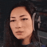 a woman wearing headphones and a microphone is looking at the camera