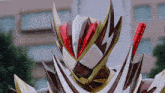 a close up of a red white and gold robot with a sword