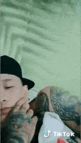 a man with a tattoo on his arm is laying on a bed with tiktok written on the bottom right