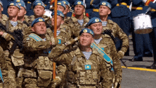 a group of soldiers are marching in a line with one wearing a badge that says ' kazakhstan '