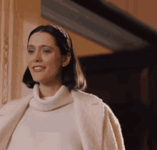 a woman wearing a headband and a white sweater is smiling