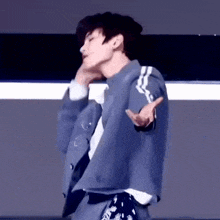 a man in a blue jacket is dancing on a stage with his hands outstretched .