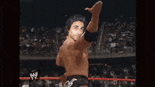 a wrestler with his fist in the air with a w logo in the background
