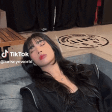 a woman laying on a couch with her eyes closed and a tiktok watermark on her face