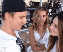 a man in a hat is talking to two women