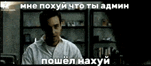 a man in a white shirt is standing in front of a shelf and talking in a foreign language .