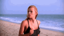 a woman in a black under armour tank top runs on the beach