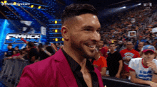 a man in a pink suit is smiling in front of a crowd at a wrestling event