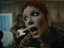 a woman with red hair singing into a microphone with her mouth open .