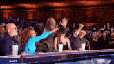 a group of people sitting at a table with a nbc logo behind them