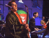 a man playing a red guitar and another man playing a keyboard on stage