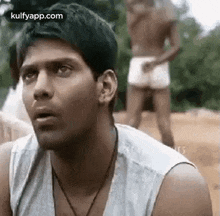 a man in a white tank top and white shorts is looking at something .