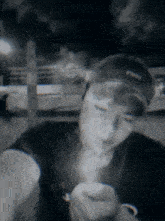 a man wearing a black hat with the word state on it smoking a cigarette