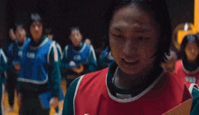 a girl in a red and green vest holds a piece of paper