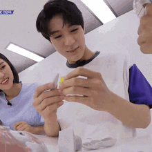 a man and a woman are sitting at a table looking at a cube .