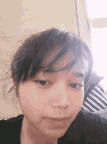 a close up of a woman 's face with a striped shirt behind her