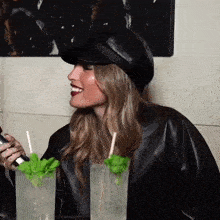 a woman wearing a black leather jacket is sitting at a table with two drinks