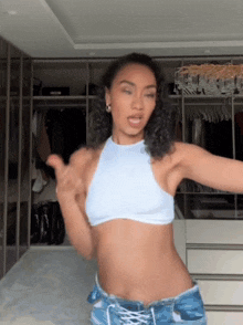 a woman wearing a crop top and shorts is dancing in a closet