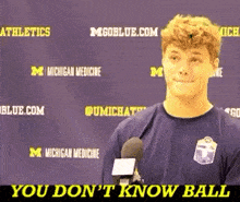 a young man is talking into a microphone in front of a purple background that says michigan medicine