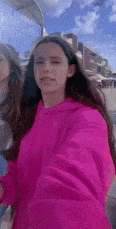 a woman in a pink hoodie is taking a selfie with a camera .