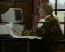 a woman sits at a desk in front of a computer screen that says itv 3 on it