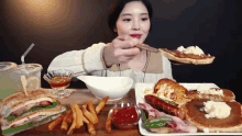 a woman is sitting at a table with a plate of food including pancakes and french fries