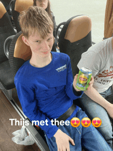 a boy in a blue shirt is holding a can of lipton