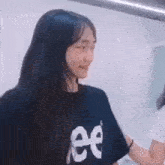 a girl wearing a black t-shirt with the letter e on it is smiling .