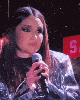 a woman holding a microphone in front of a sign that says sa