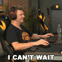 a man wearing headphones sits at a desk with the words " i can 't wait " written below him