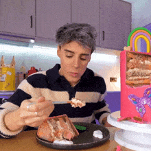 a man in a striped shirt is eating a slice of cake