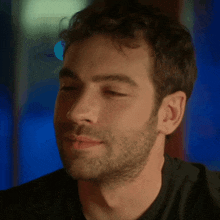 a man with a beard wearing a black shirt is smiling with his eyes closed