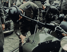 a man in a military uniform is looking at a gun on a motorcycle