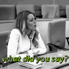 a woman sits at a table with the words " what did you say " on the bottom